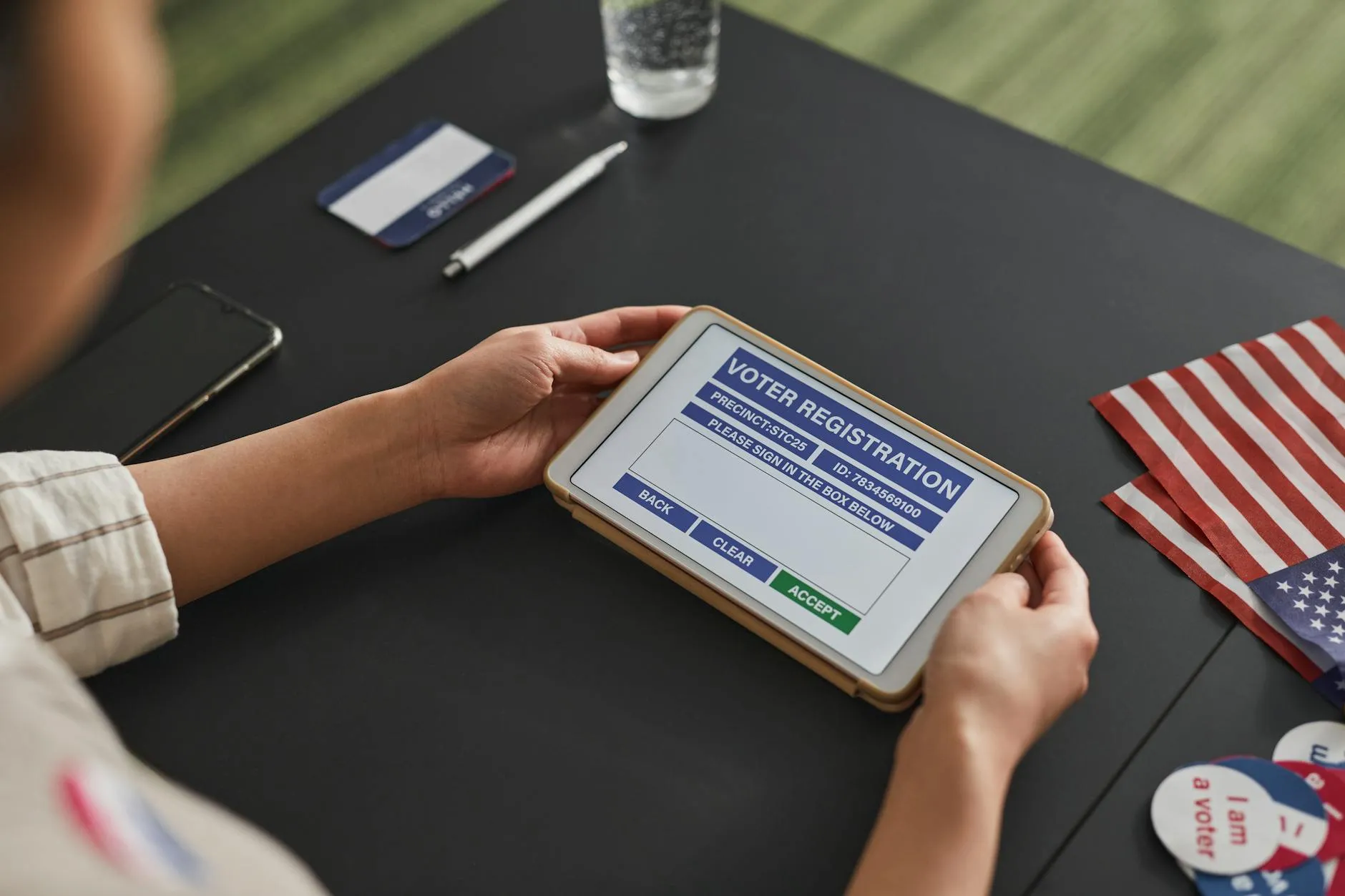 Close-up of a student's hands creating digital flashcards on a tablet at a slightly messy dorm desk.