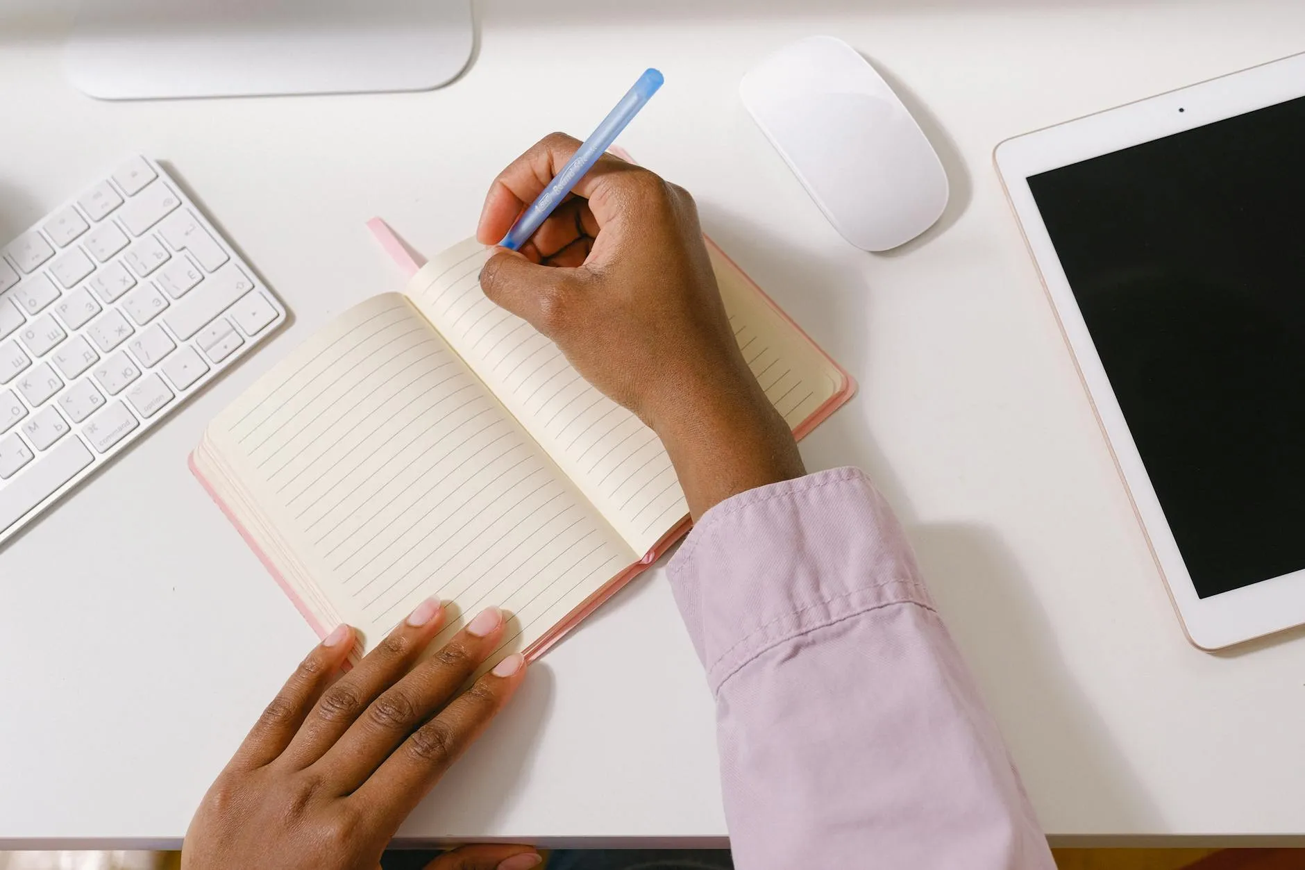 Close-up of student's hands creating digital flashcards on a tablet amidst a messy dorm desk