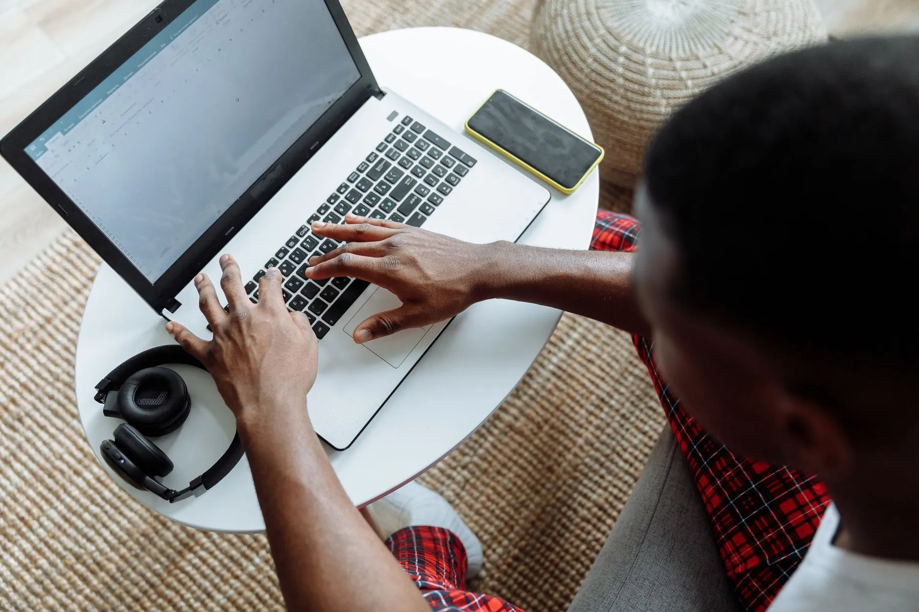 Close up of hands typing on a laptop on a messy student desk with a coffee cup
