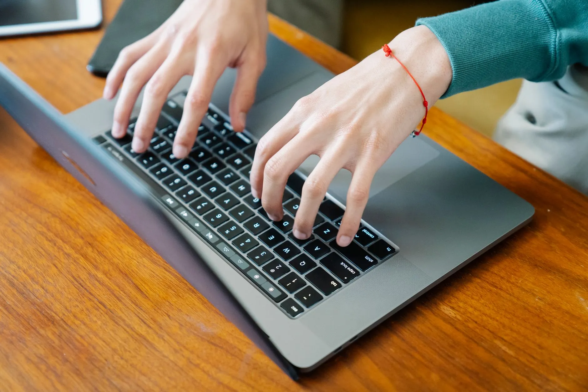 Close up of student hands typing on a laptop on a messy dorm room desk with notebooks