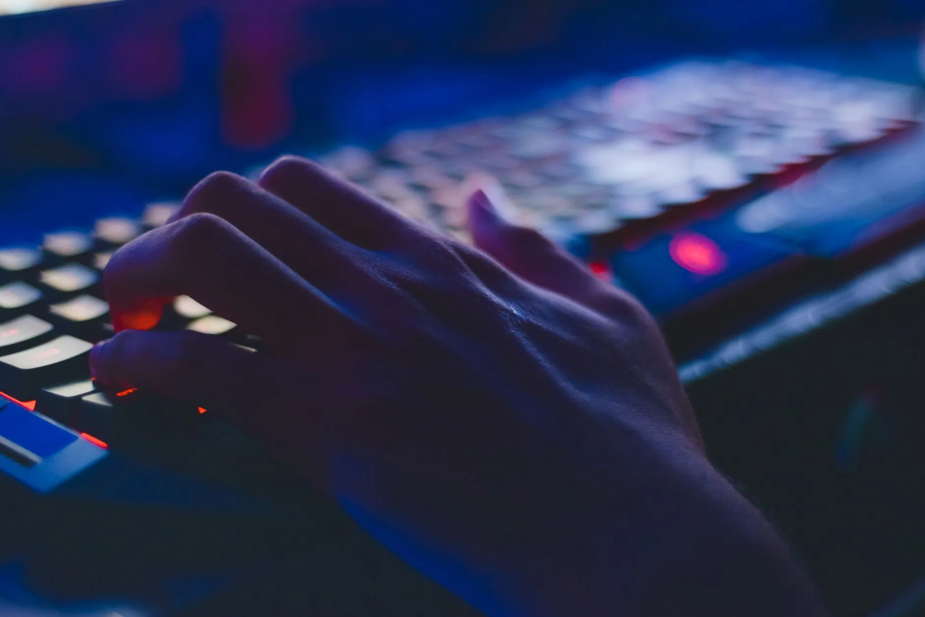 Close up of student hands typing on a laptop keyboard on a messy dorm room desk with coffee