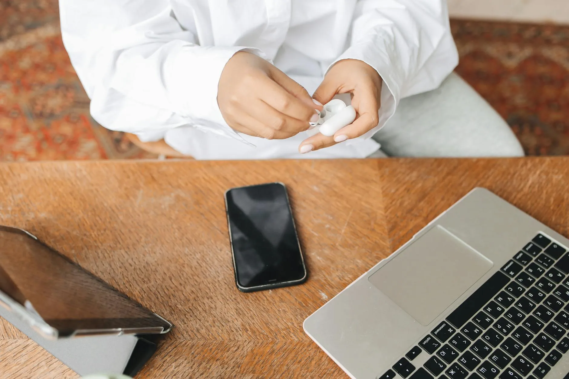 Close-up of a student's hands creating digital flashcards on a tablet amidst a messy but cozy dorm room desk.