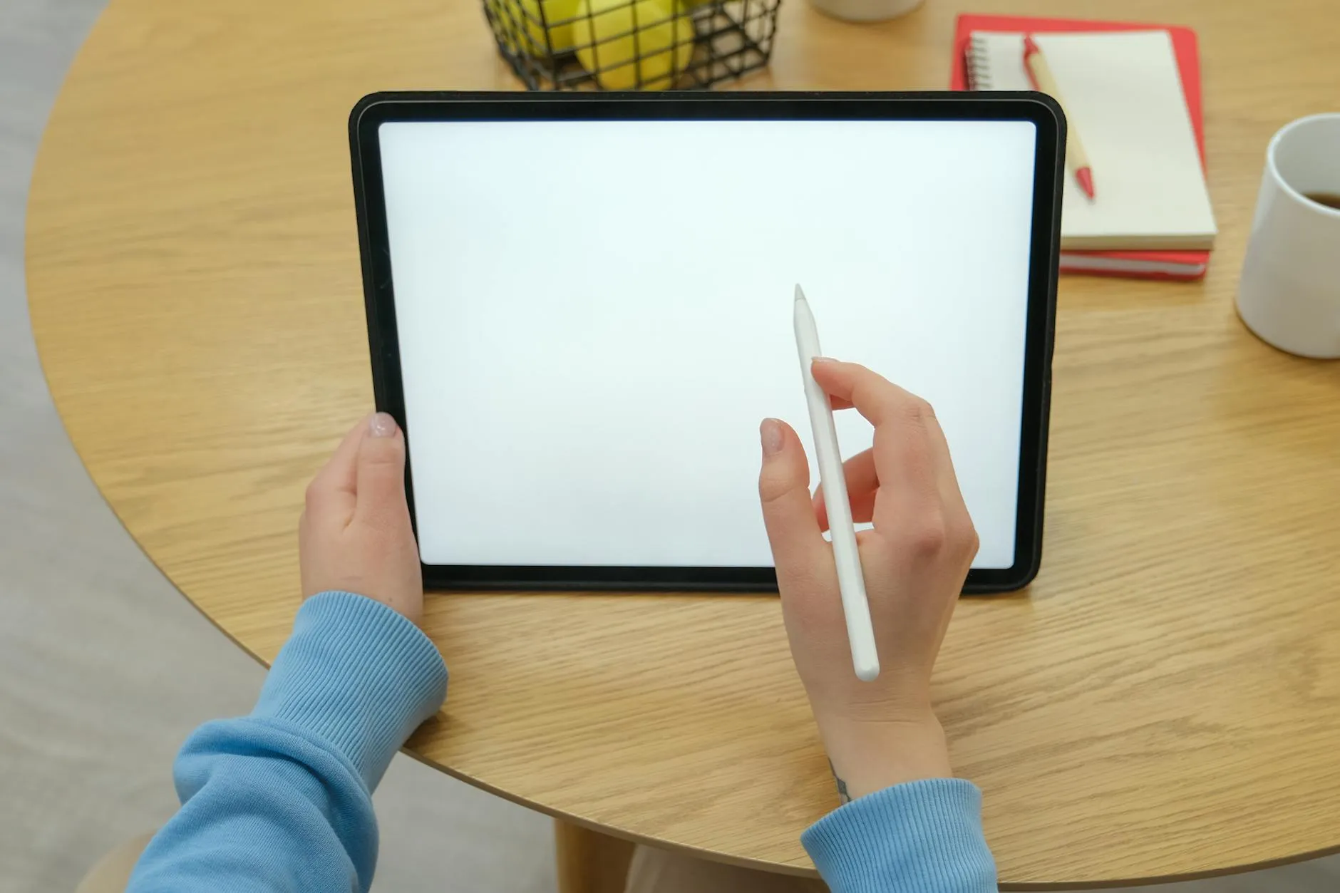 Detail shot of a student taking digital notes on a tablet surrounded by study materials