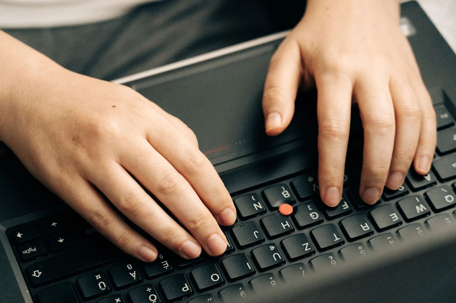 Close up of student hands typing notes on a laptop while referencing lecture slides on a tablet