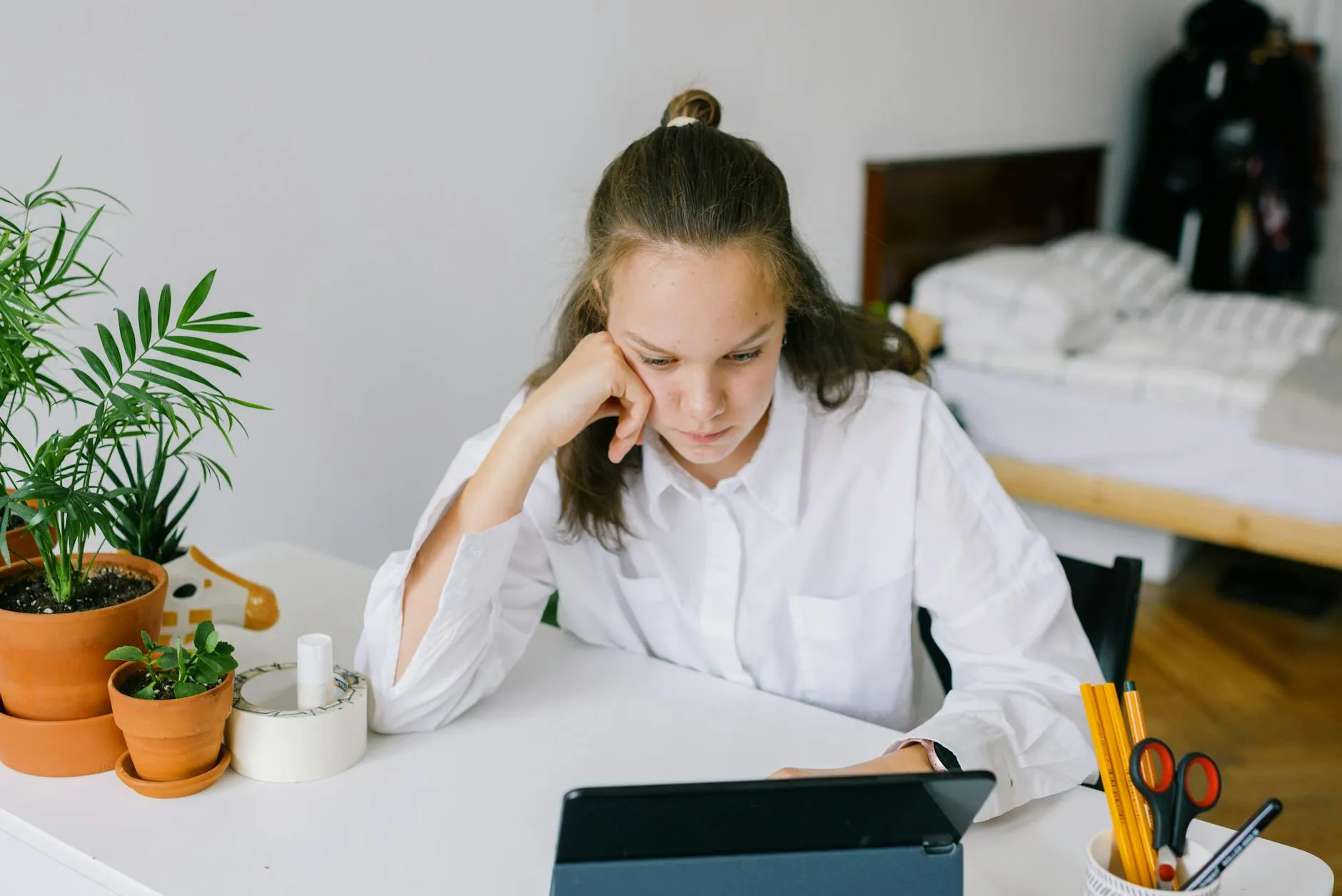 Close-up of a student's hands creating flashcards on a tablet at a messy dorm desk