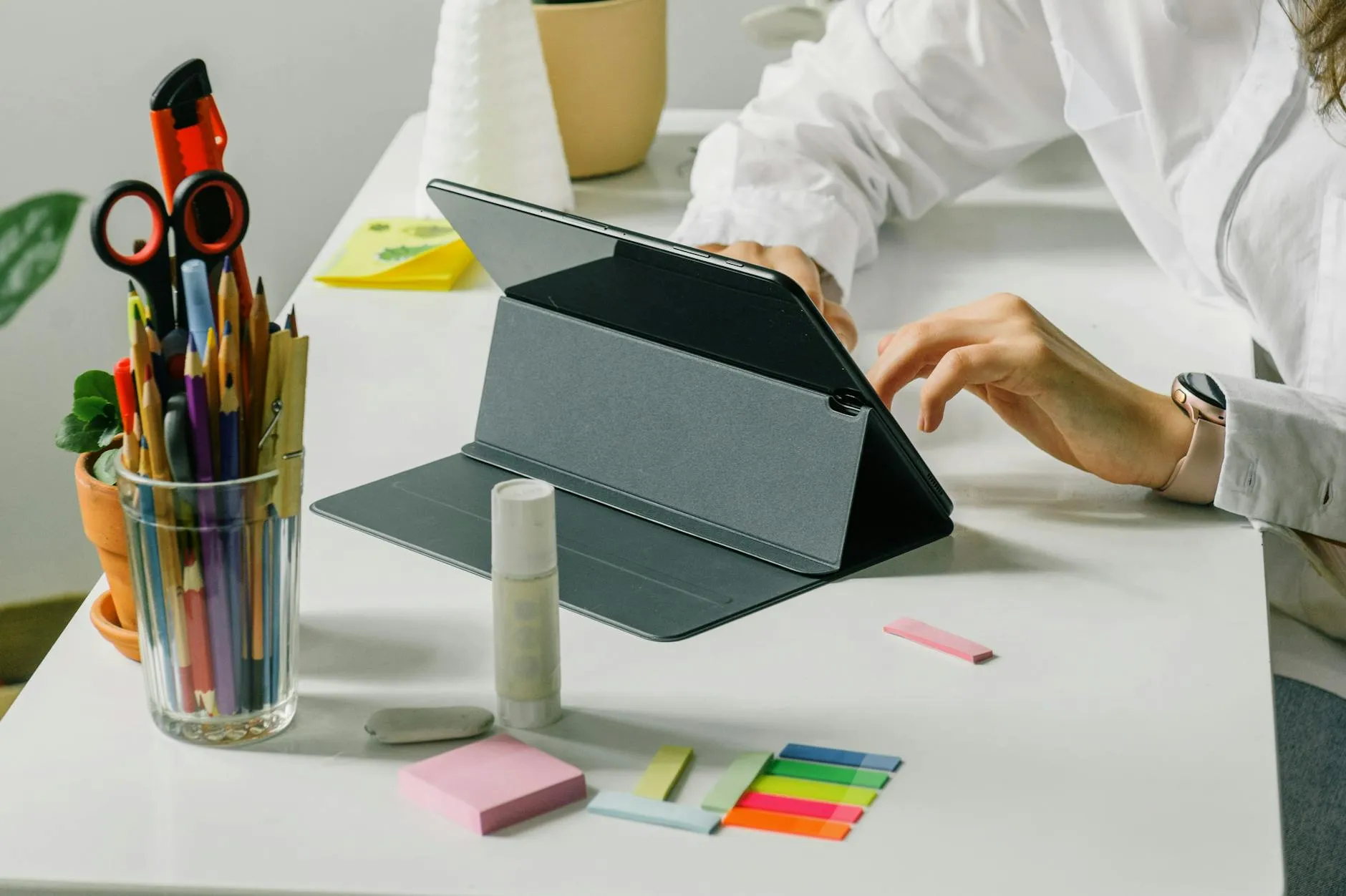 Detail shot of a student using a tablet to organize digital study materials on a cluttered desk