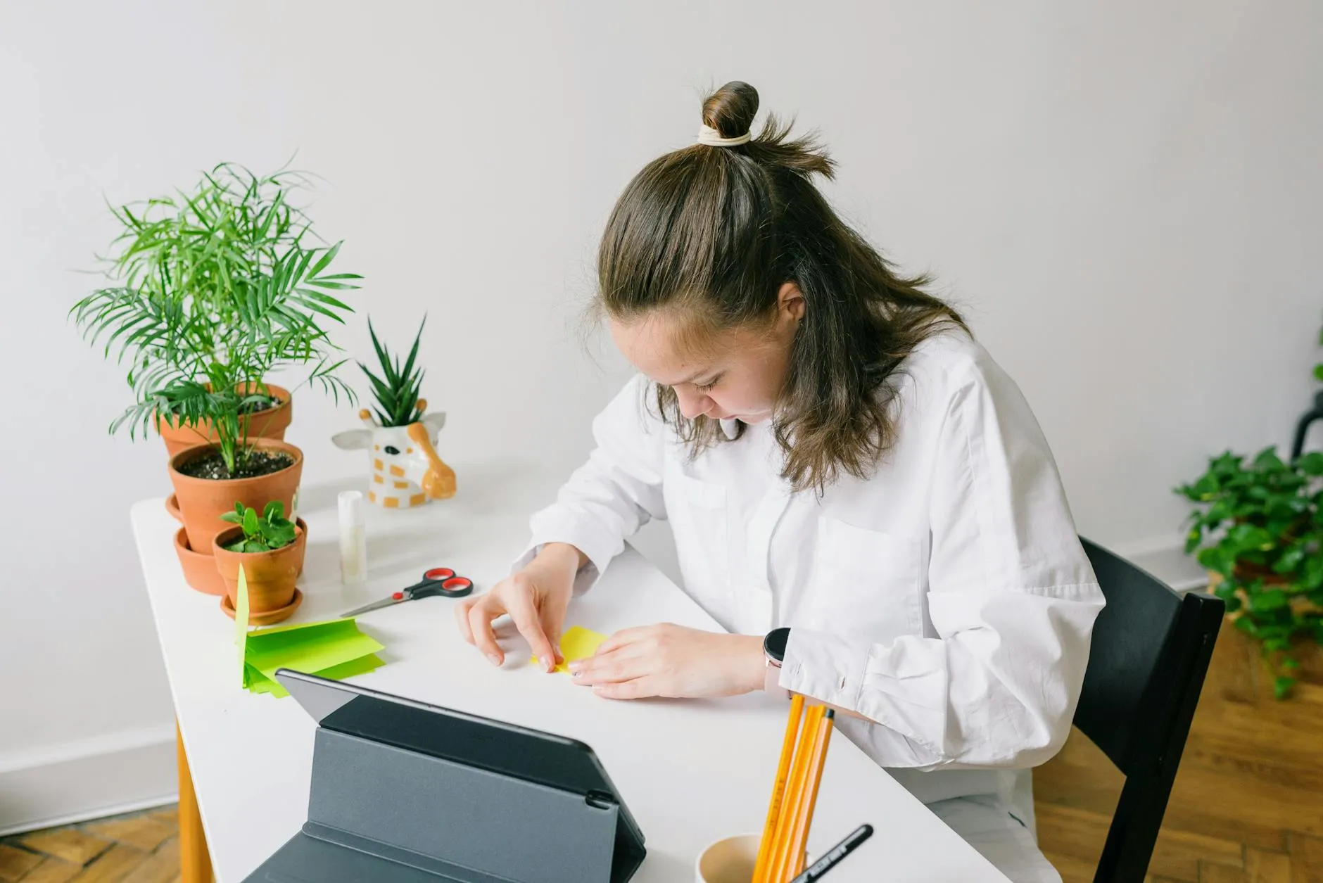 Close up of a student using a tablet to organize digital study materials on a messy desk