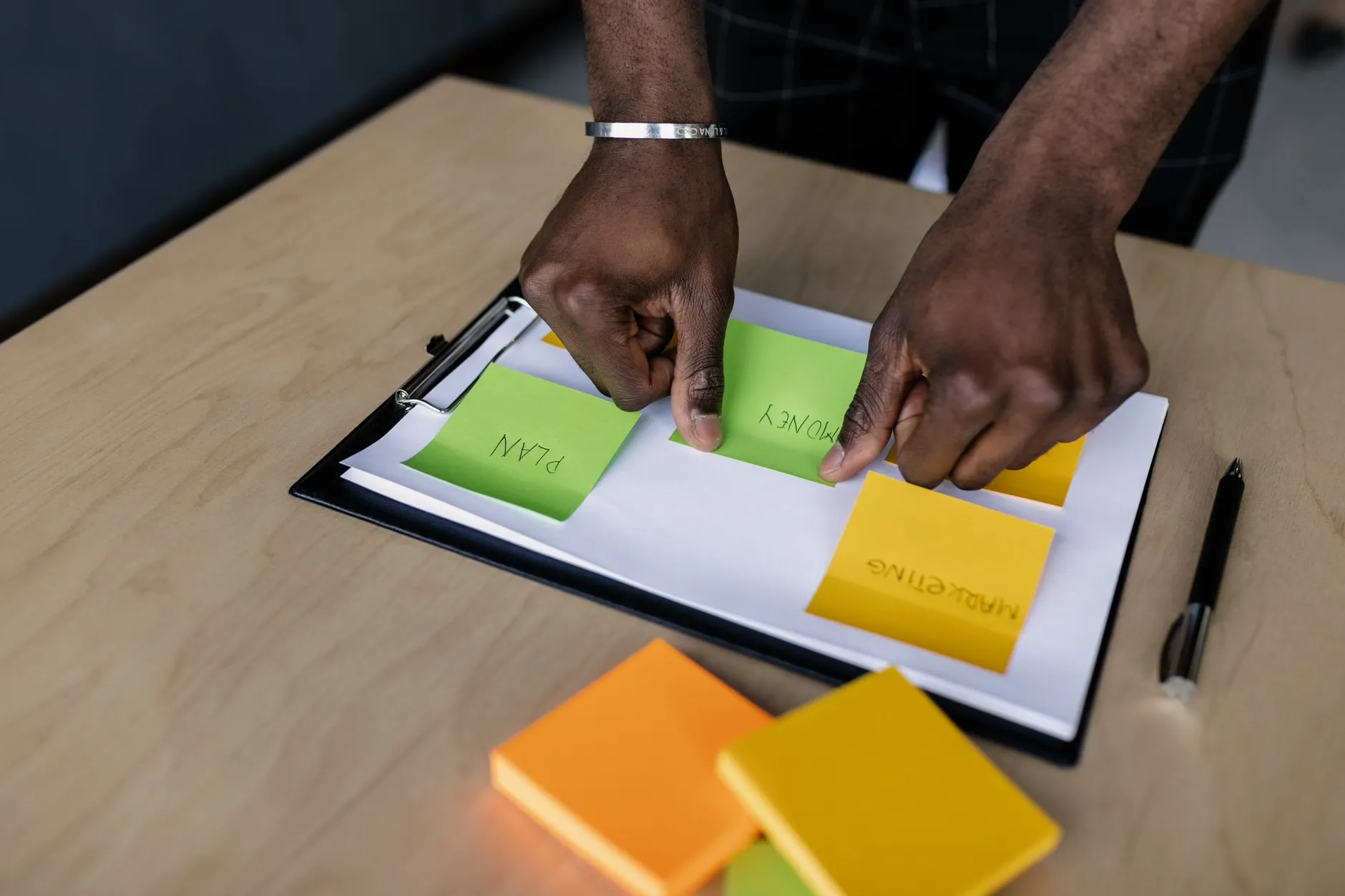 Hands using a tablet to generate digital flashcards on a messy study desk