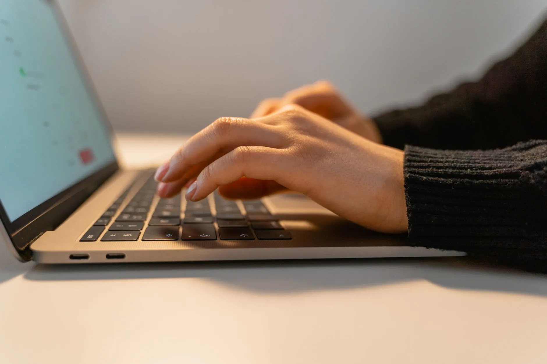 Close up shot of a student hands typing on a laptop next to a tablet displaying digital flashcards on a messy study desk