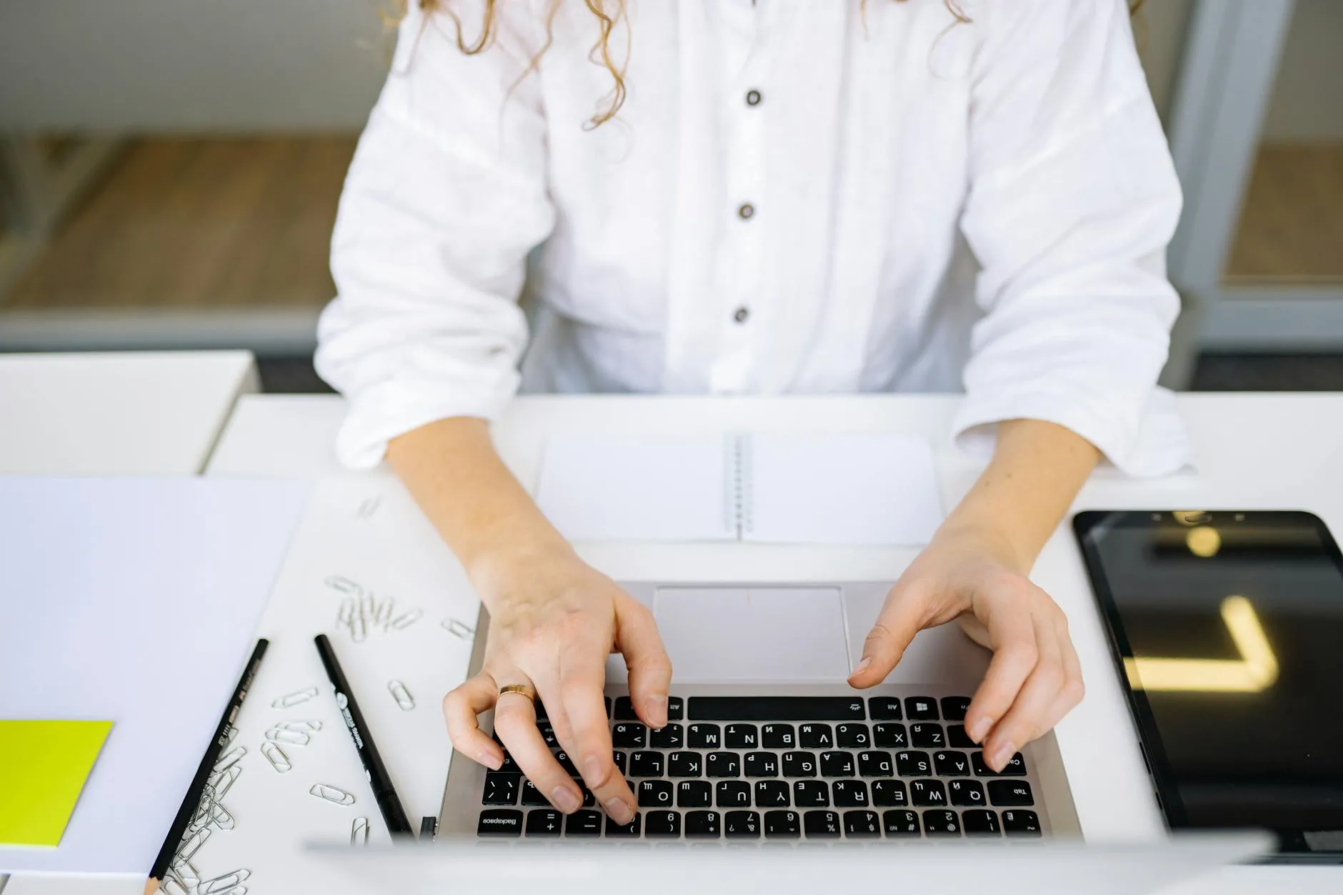 Close-up of student's hands using a tablet to create flashcards on a messy dorm room desk.