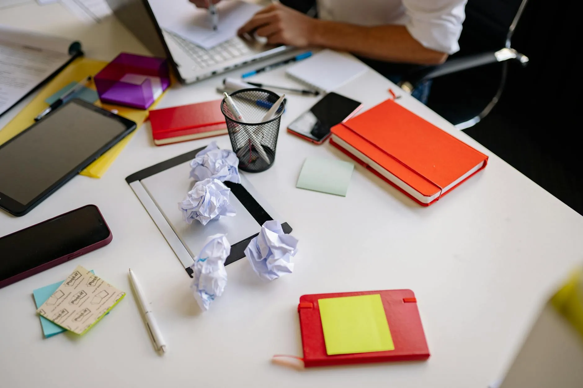 Close up of a student using a tablet to create digital flashcards on a messy dorm room desk