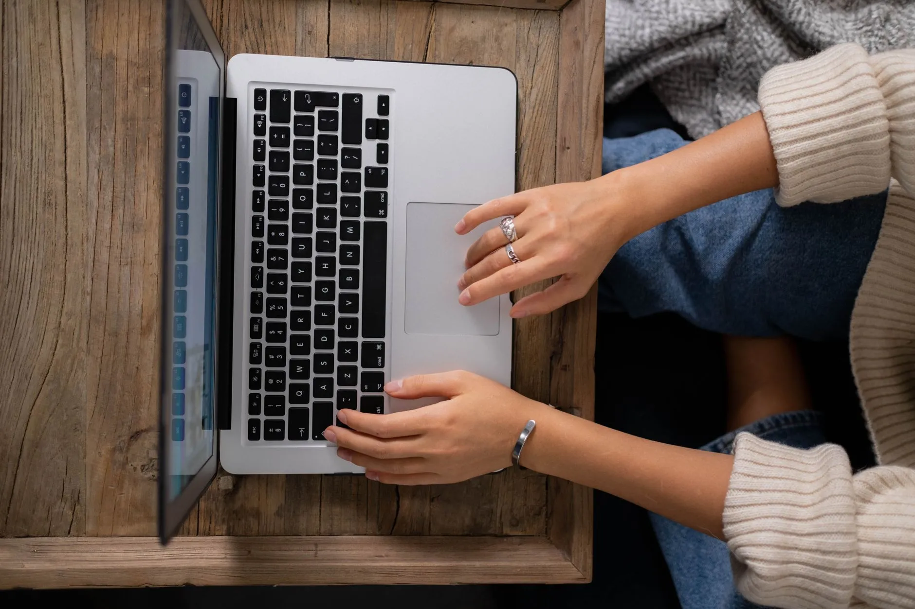Close up of student hands typing on a laptop surrounded by psychology study guides on a messy desk