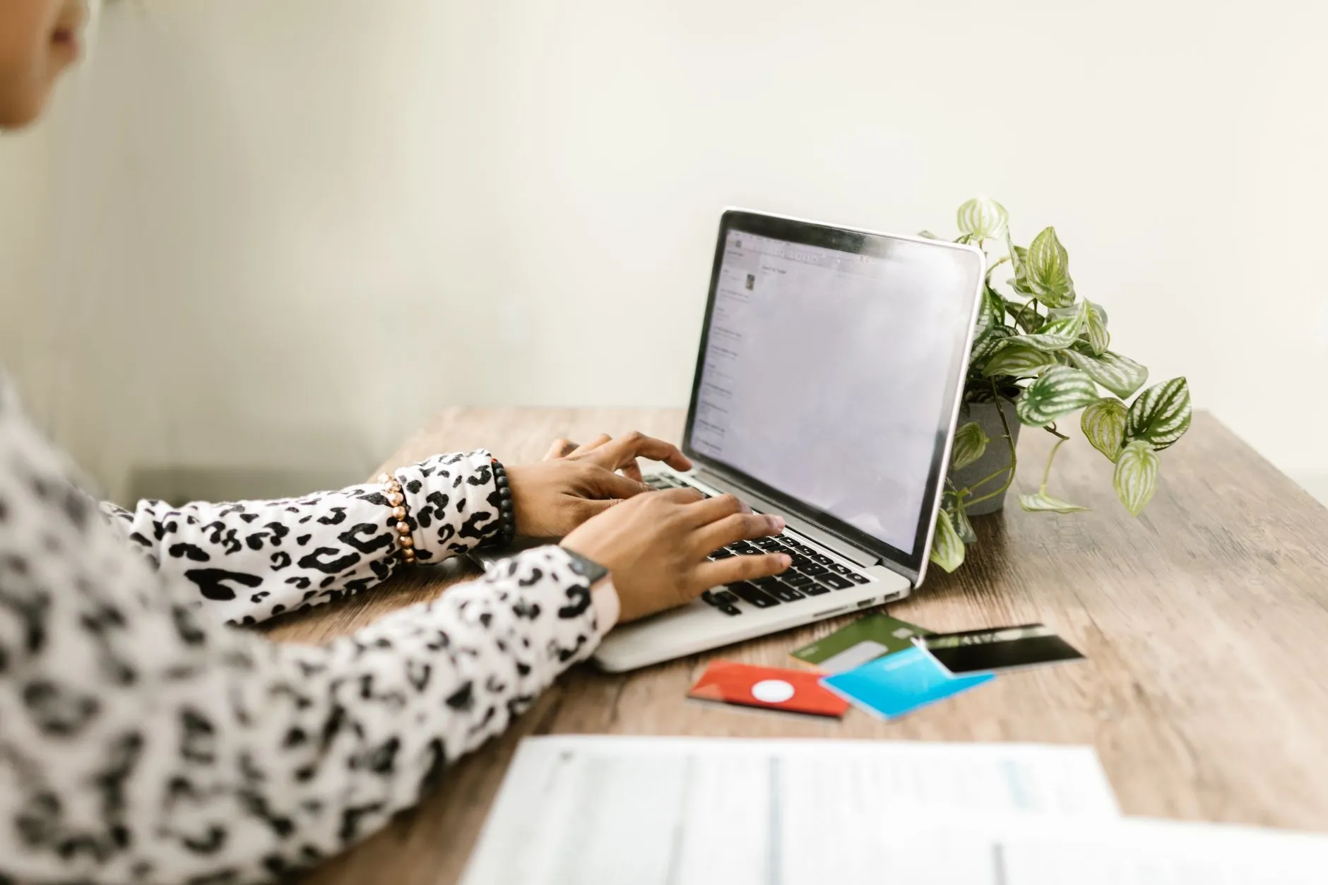 Close up of a student typing on a laptop with notebooks and coffee on a messy desk