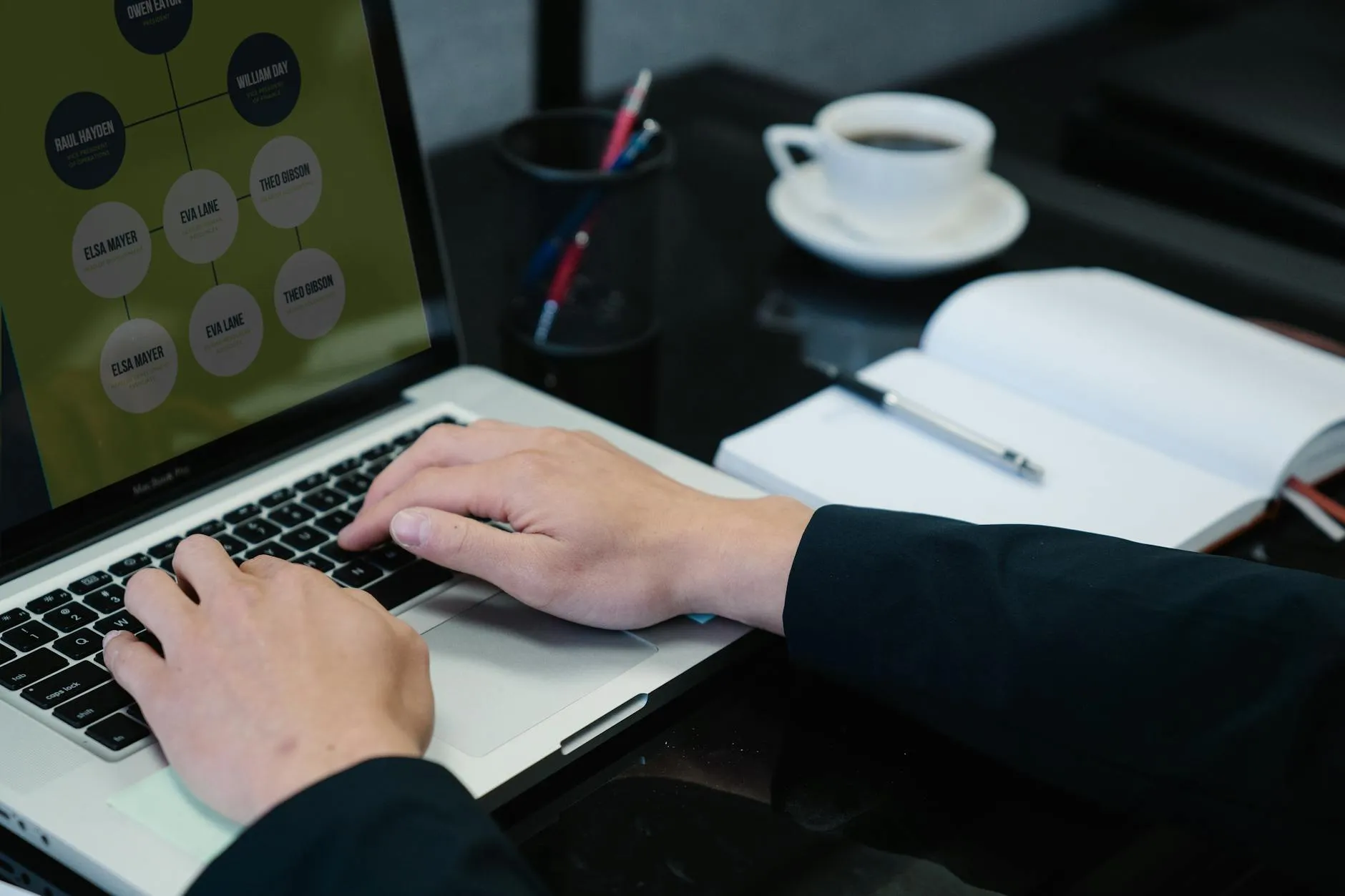 Detailed shot of a student working on a laptop surrounded by study materials