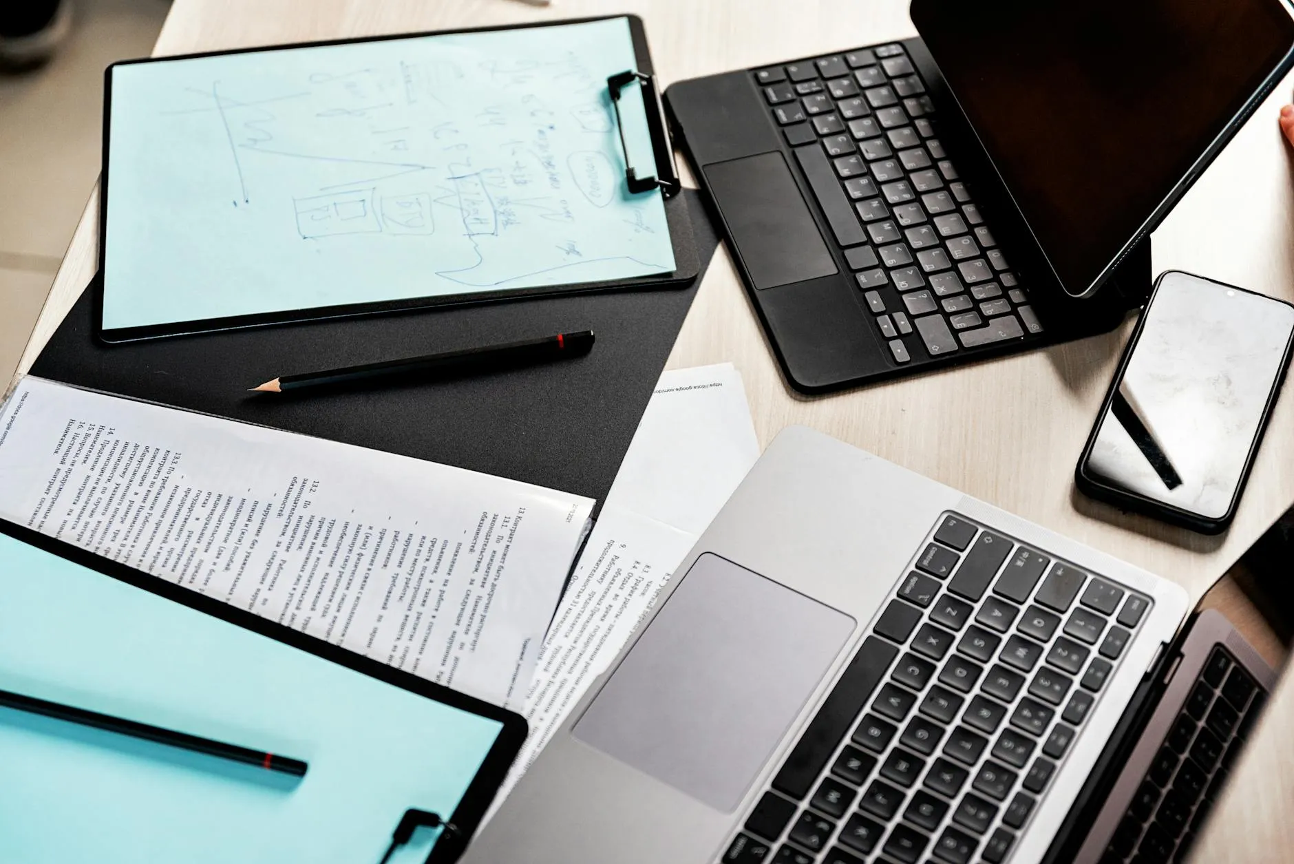 Close up of a student using a tablet and laptop to organize study materials