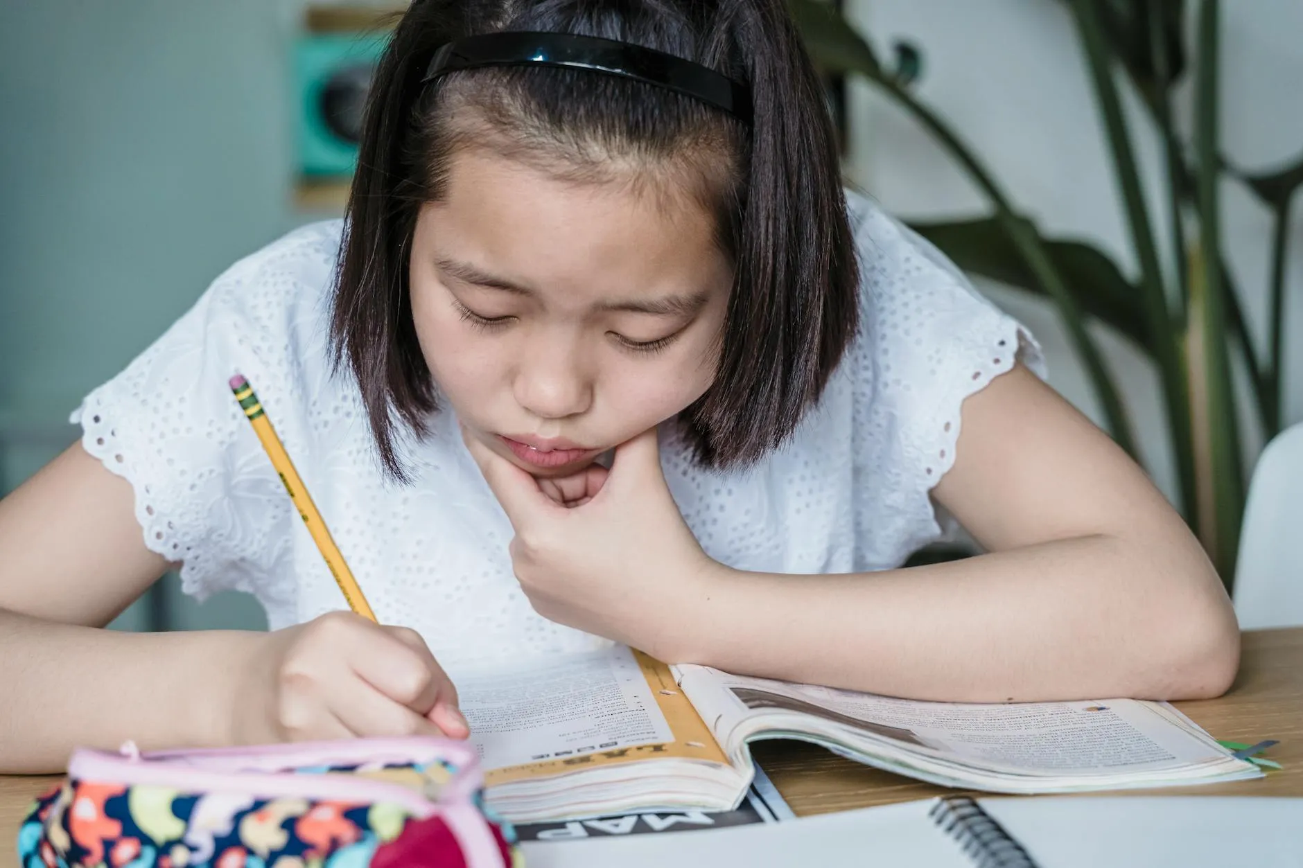 A focused student studying alone at a messy desk in a cozy dorm room, surrounded by books and notes.