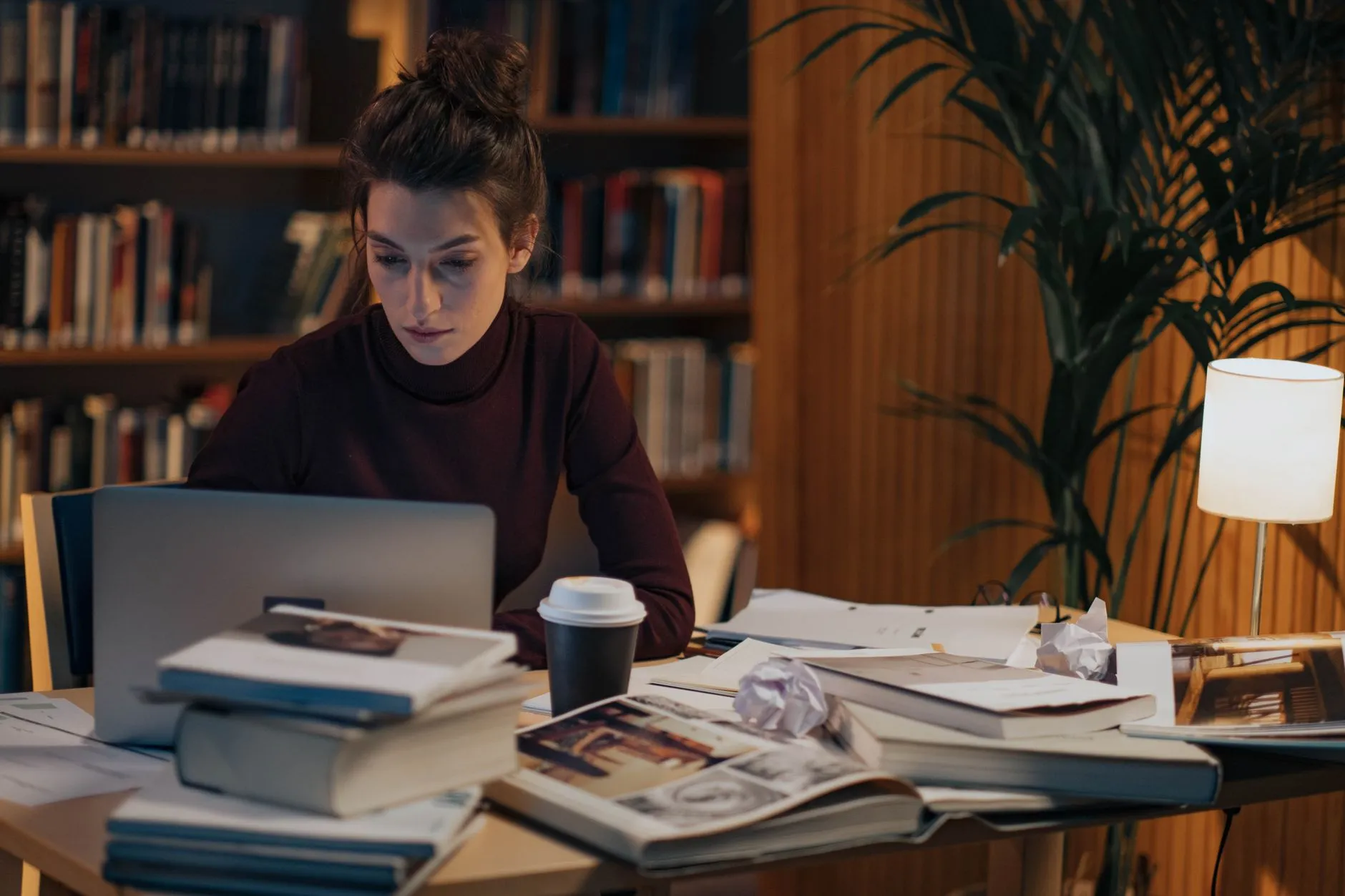 A student organizing their study space with a laptop and notebooks under warm lighting