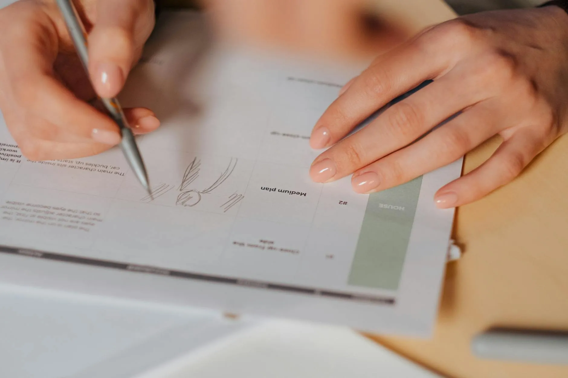Close up of a student's hands writing in a paper planner on a wooden desk