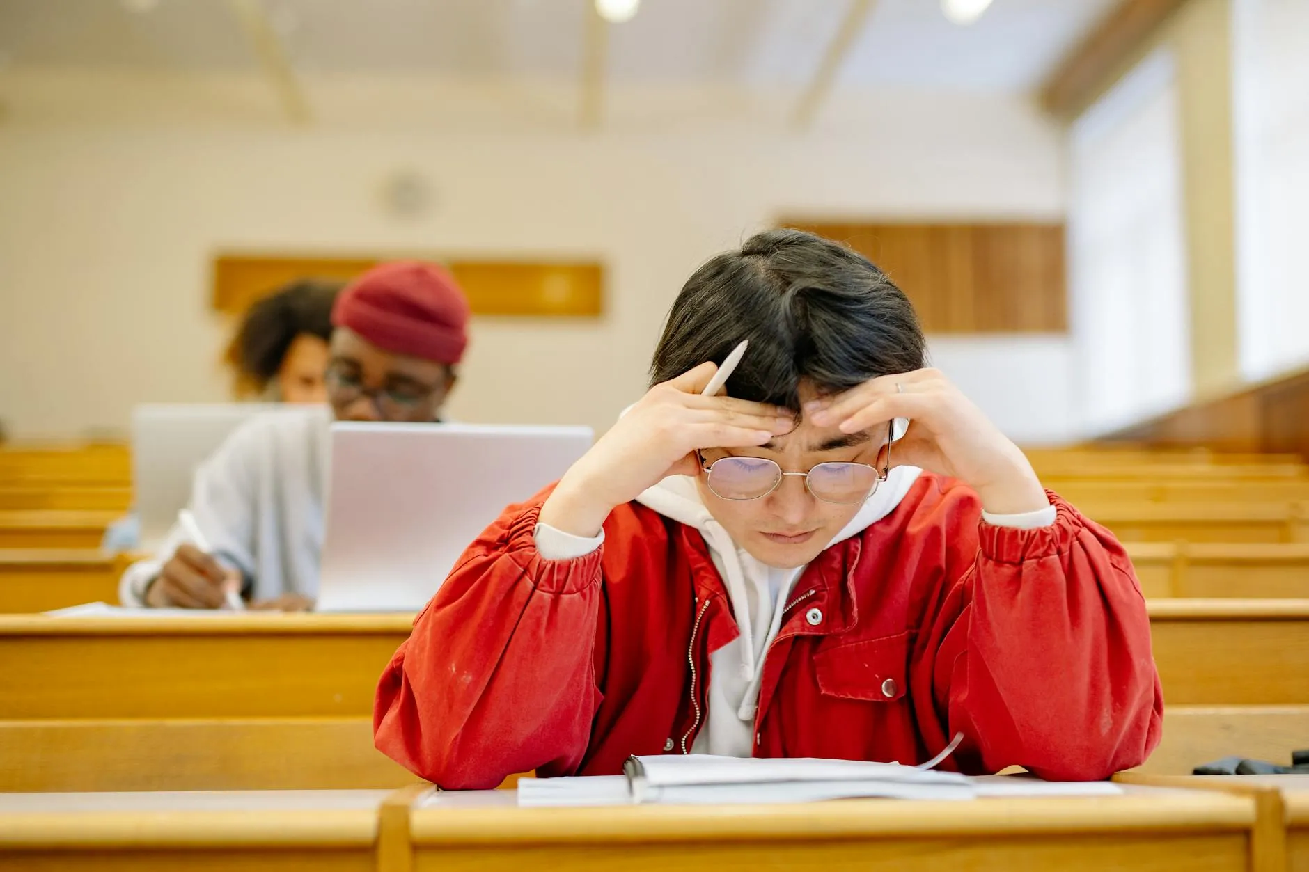 Close-up of student's hands typing notes on a tablet in a modern library lecture hall