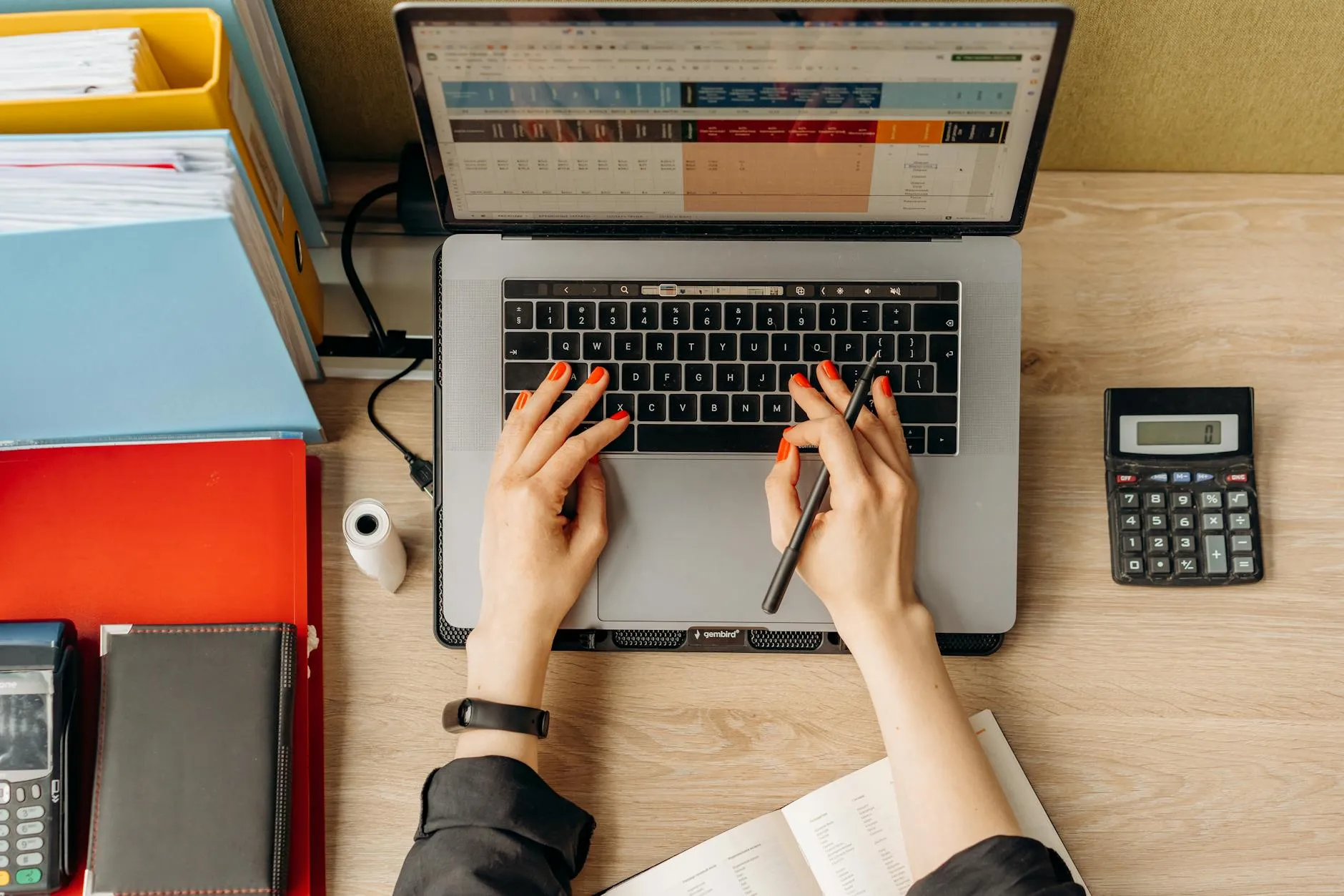 Close up of student hands typing on a laptop surrounded by notebooks on a cozy dorm desk