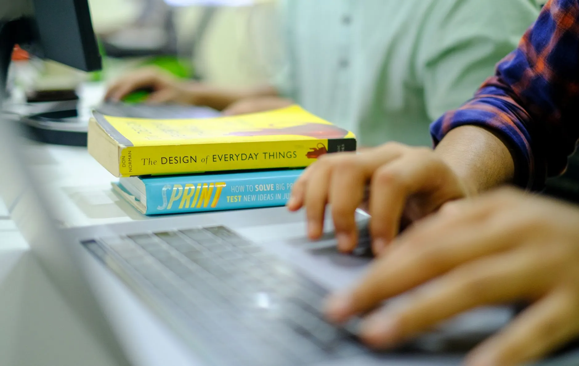 Close up shot of a student hands typing on a laptop keyboard surrounded by notebooks and coffee on a messy study desk