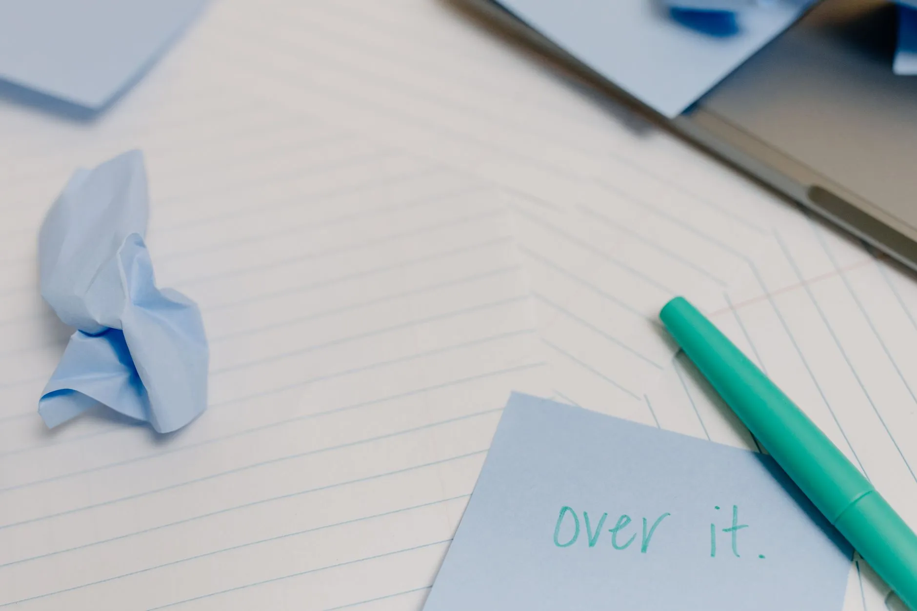 Close-up of a student's hands taking notes on a tablet next to a phone recording audio on a messy desk.