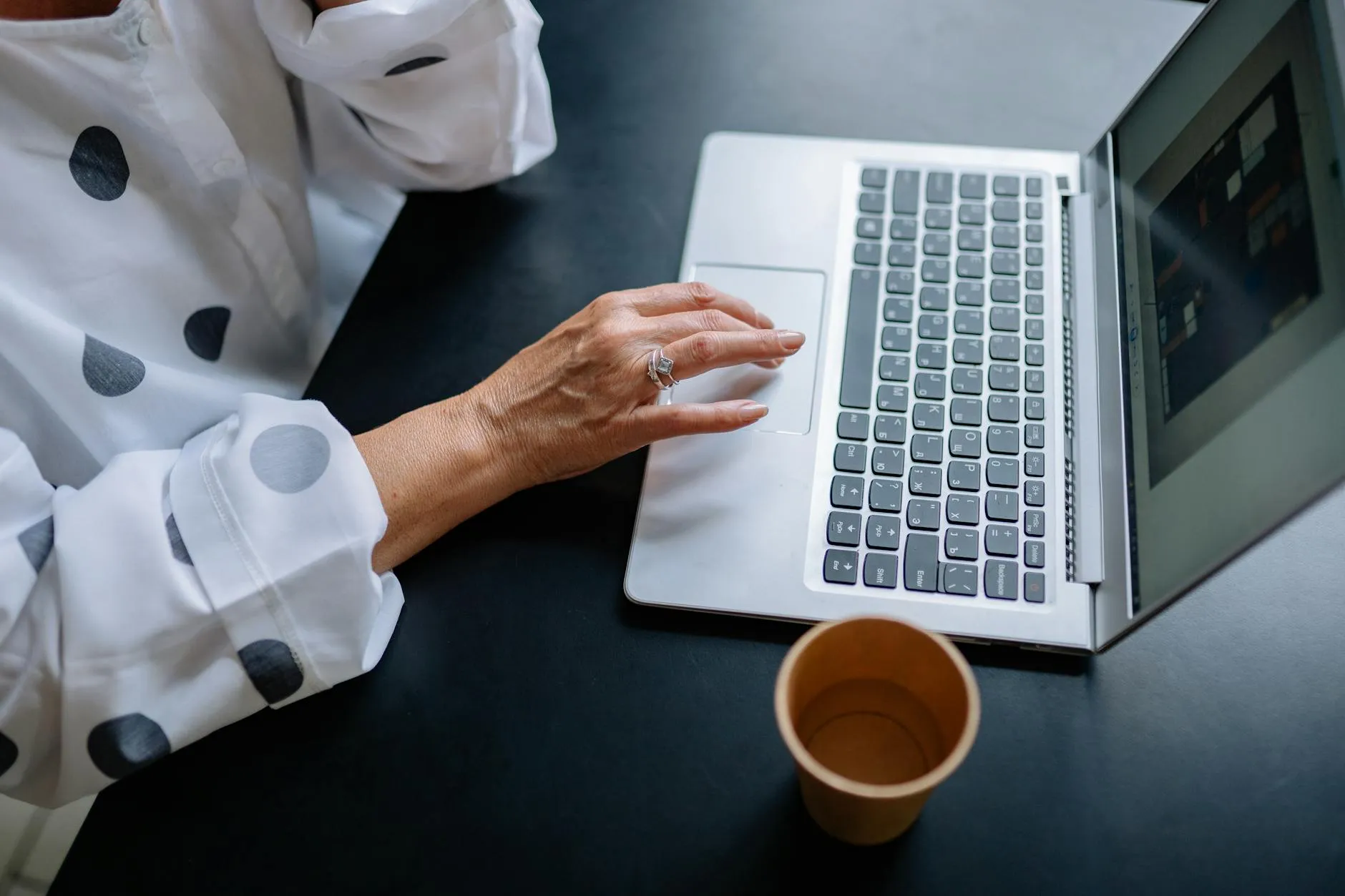 Close-up of a student's hands typing notes on a laptop at a messy dorm desk, emphasizing personal note-taking.